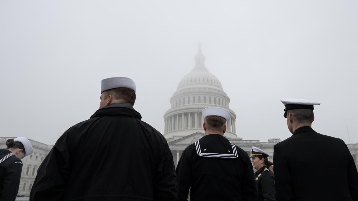 service members walk in front of a foggy US Capitol building