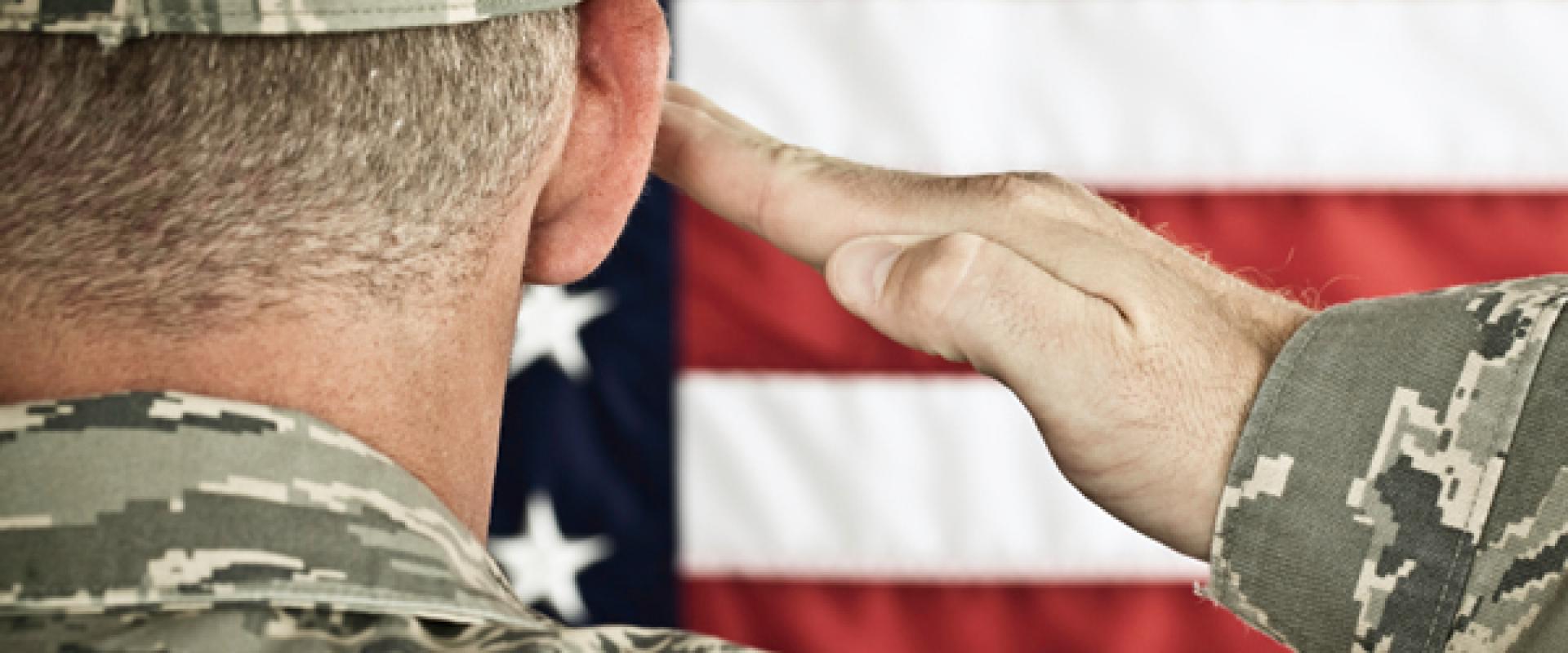 Military soldier saluting an American flag